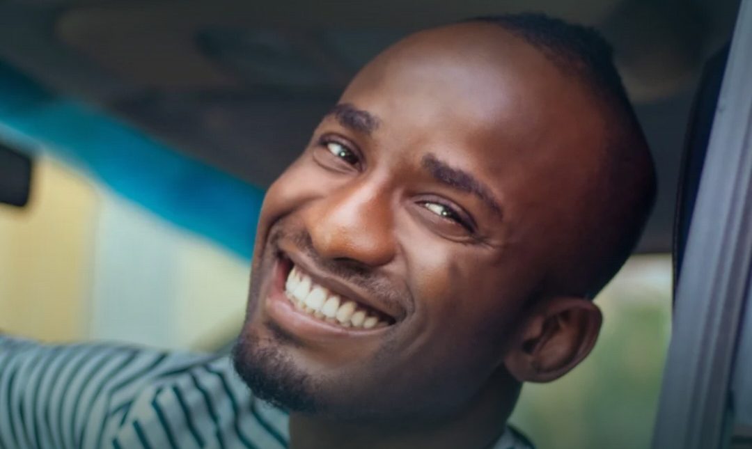 A driver leaning out of the car window, laughing