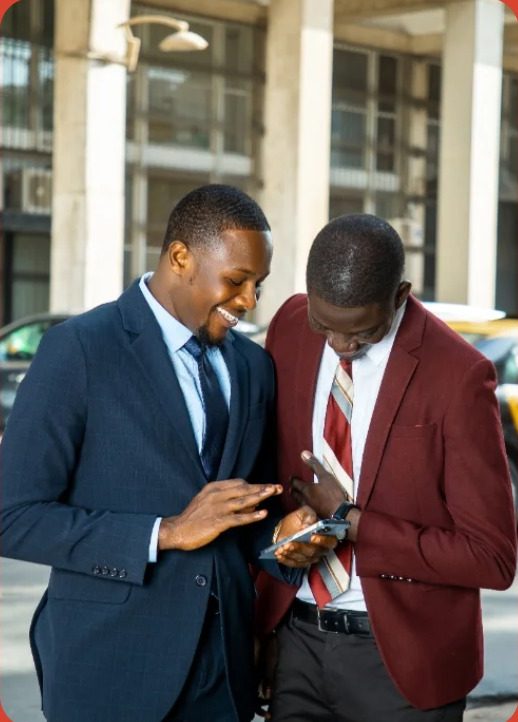 Two colleagues laughing over a phone at the roadside